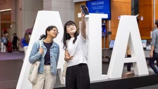 Two women taking a selfie in front of AIA logo