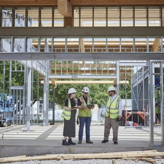 Three people reviewing plans at a construction site