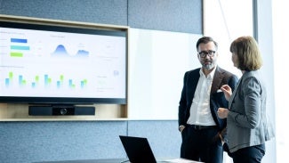 Man and woman working together looking at a screen with charts