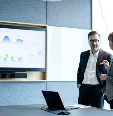 Man and woman working together looking at a screen with charts