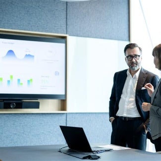 Man and woman working together looking at a screen with charts