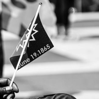A hand holding the Juneteenth flag