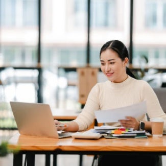 Woman at her desk working on her resume through her laptop