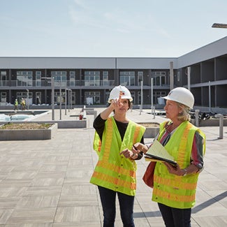 Architects in PPE gear evaluating a project at a construction site.
