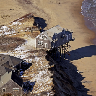 An aerial view of a building on pilings compromised by coastal erosion Truro, Mass.