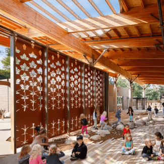Exterior space with a wooden roof and a metal dividing wall cut out with leaf shapes
