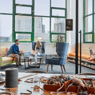 Interior of office building with large glass windows, two people sit in chairs