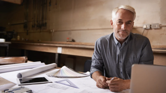 A man sitting at a desk with architecture drawings on the table